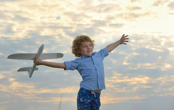 Little boy holding a wooden airplane model on field — Stock Photo, Image