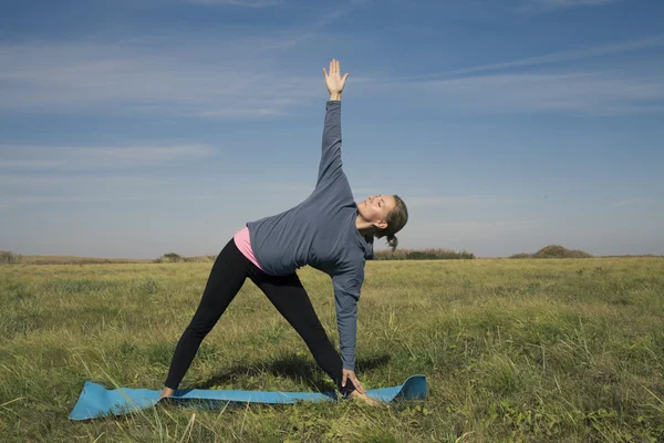 Yoga posa bionda giovane donna di bellezza su erba verde — Foto Stock