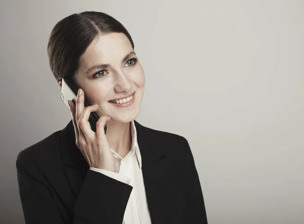 Бізнес молода усміхнена жінка на телефоні ізольована над сірим б — стокове фото
