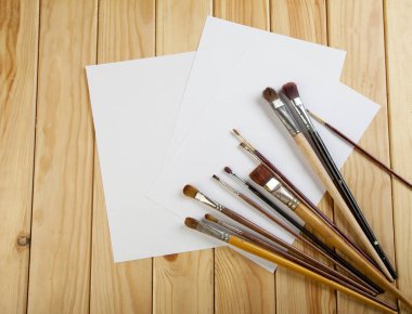 Fırçalar ve üç beyaz kağıdın ahşap bir masa üzerinde