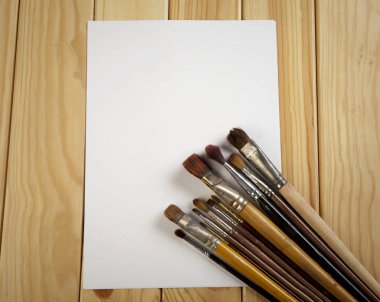 Fırçalar ve ahşap bir masa üzerinde beyaz kağıdın