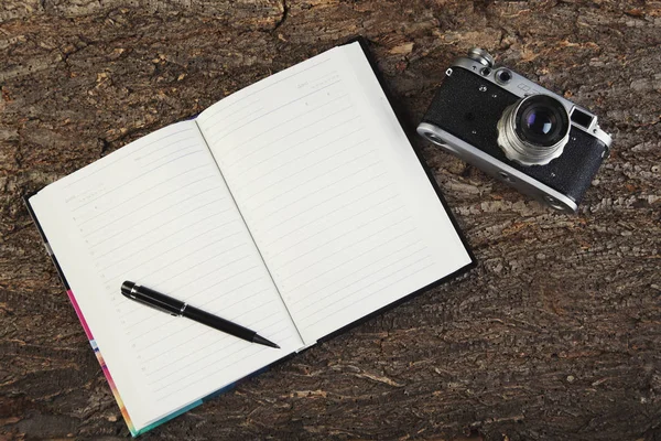 Starý fotoaparát a deník na dřevěné pozadí horní pohled — Stock fotografie