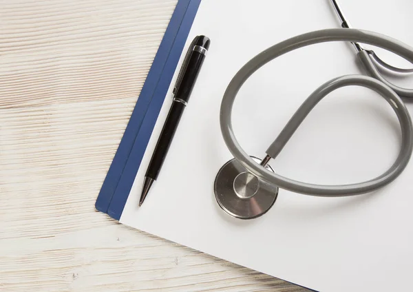 White wooden background with medic Stethoscope paper and pen vie — Stock Photo, Image