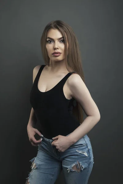 Young woman in jeans and shirt on dark background — Stock Photo, Image