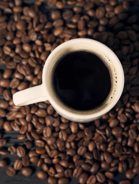 Grãos de café e xícara em um preto velho bg de madeira vista superior — Fotografia de Stock