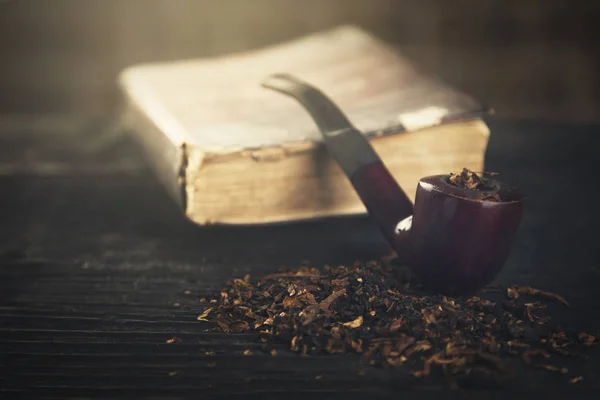 Pipe smoking tobacco old book on black wooden toning light effec — Stock Photo, Image