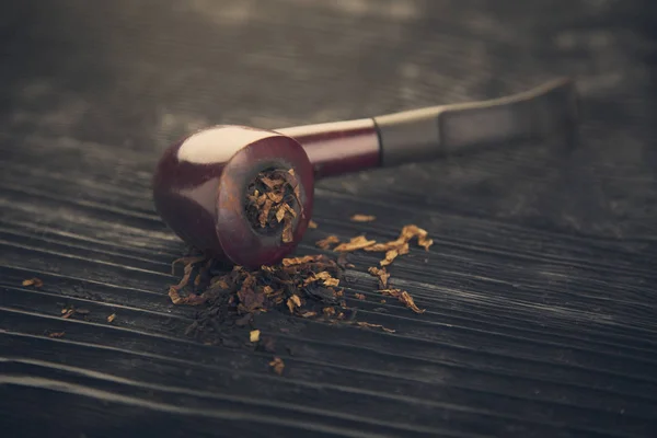 Pipe smoking tobacco on a wooden black bg — Stock Photo, Image