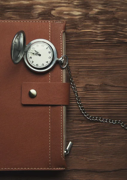 Шкіряний щоденник і ретро годинник на дерев'яному коричневому фоні фото — стокове фото