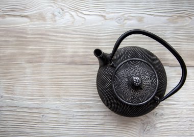 Beyaz ahşap arka planda siyah metal çaydanlığı.