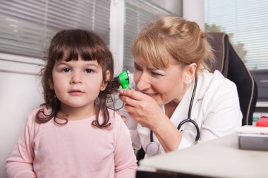 Çocuk doktoru bir çocuğu ziyaret ediyor.