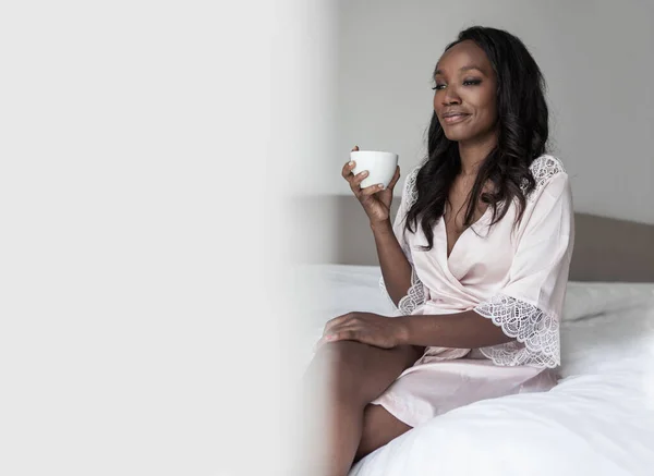 Mujer está bebiendo café en la cama —  Fotos de Stock