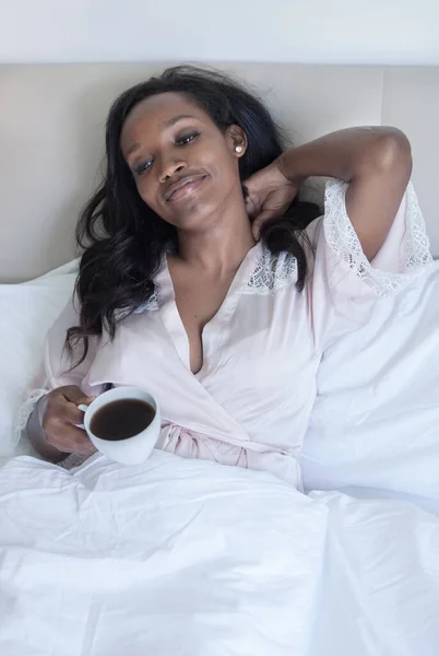 Mujer está bebiendo un café en la cama —  Fotos de Stock