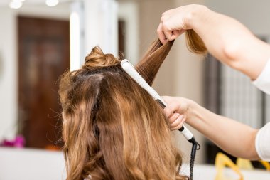 Profesyonel Kuaför Saç maşası kullanarak. Saç güzellik salonunda bukleler