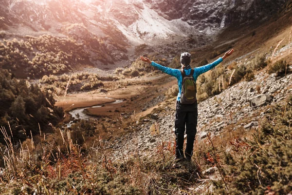Mulher com mochila em pé em uma trilha de outono de montanha com as mãos levantadas, conceito de sentimento de sucesso — Fotografia de Stock