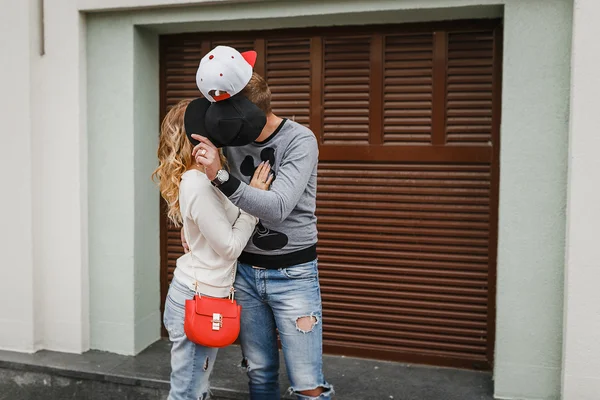 Hipster casal apaixonado esconder atrás de bonés e beijos — Fotografia de Stock