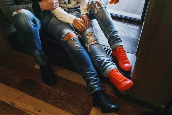 Snygg man och kvinna i kärlek kramar. Närbild av rippade jeans och sneakers. Begreppet ett stil-par — Stockfoto