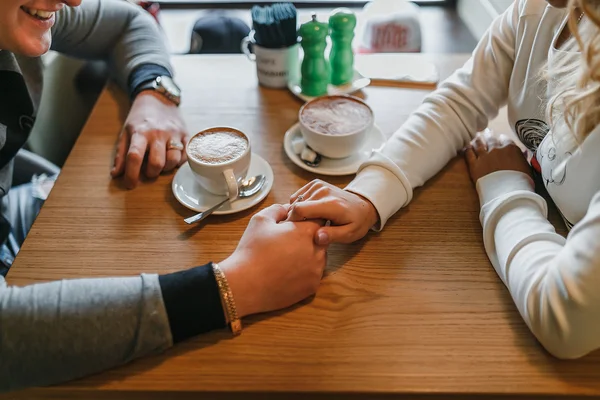 Dvě ruce milující pár a šálek kávy v kavárně roztomilé — Stock fotografie