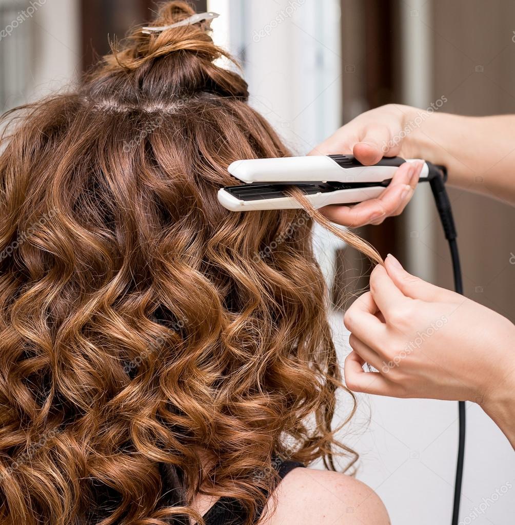 Professional hairdresser using curling iron. Hair curls in beauty salon  Stock Photo by ©frantic00 127406014