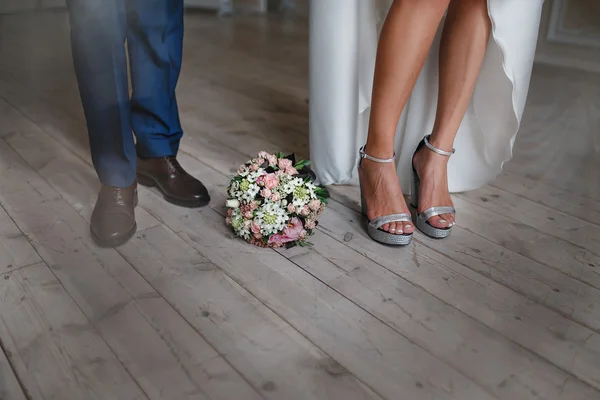 Pés de noiva e noivo em sapatos de casamento no chão com buquê — Fotografia de Stock