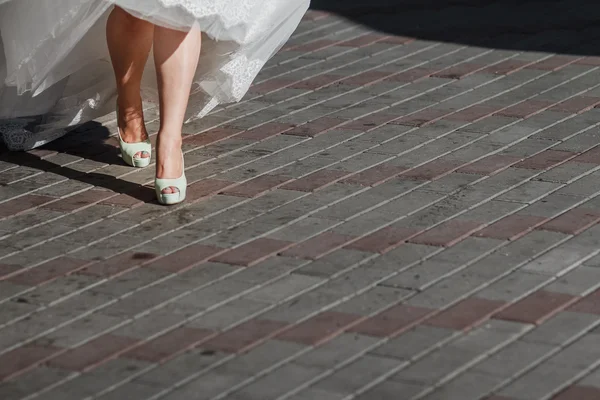 Krásná nevěsta boty s dlouhýma nohama v bílých svatebních šatech — Stock fotografie