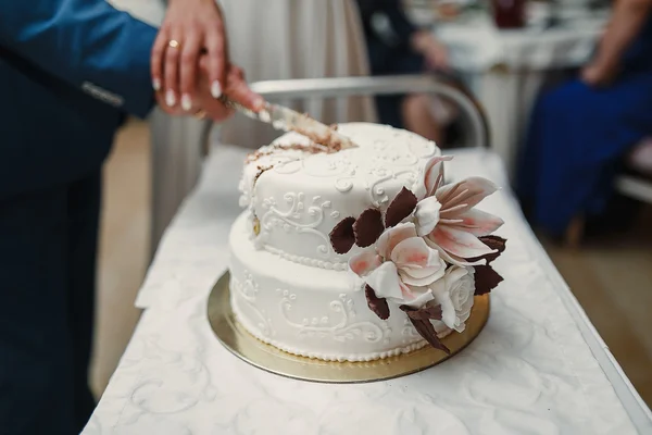 Noiva e noivo na recepção do casamento cortando o bolo de casamento — Fotografia de Stock