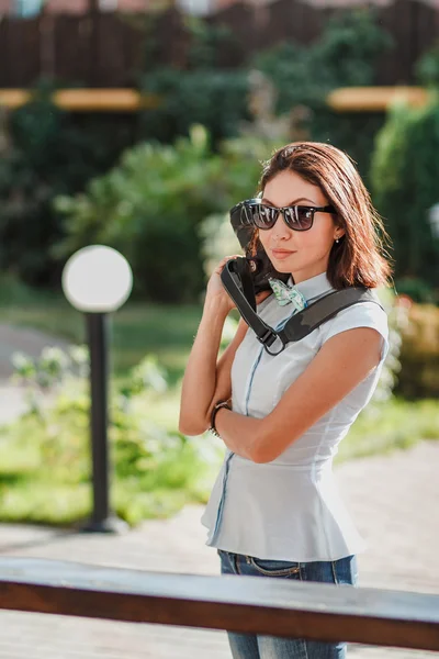 Glückliche junge Frau mit Sonnenbrille hält moderne Digitalkamera in der Hand — Stockfoto