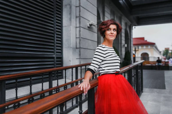 Portrait of a gorgeous brunette woman with wavy hair and beautiful smile in attractive red skirt — Stock Photo, Image