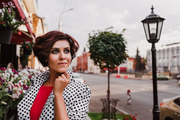 A beautiful caucasian female wearing white summer dress with black polka dots in a small european town — Stock Photo, Image