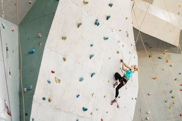 Спортивна молода жінка займається в барвистому скелелазіння спортзал — стокове фото