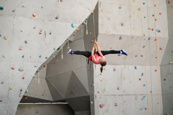 Active happy woman hanging on trope in the artificial climbing wall, doing split — Stock Photo, Image