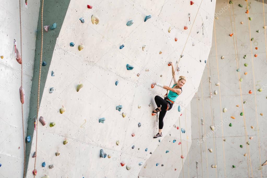 Sporty young woman exercising in a colorful climbing gym