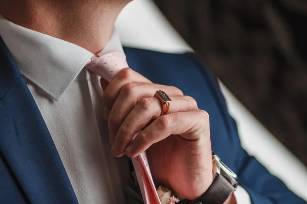 Closeup of a corporate man adjusting his fashionable pink necktie