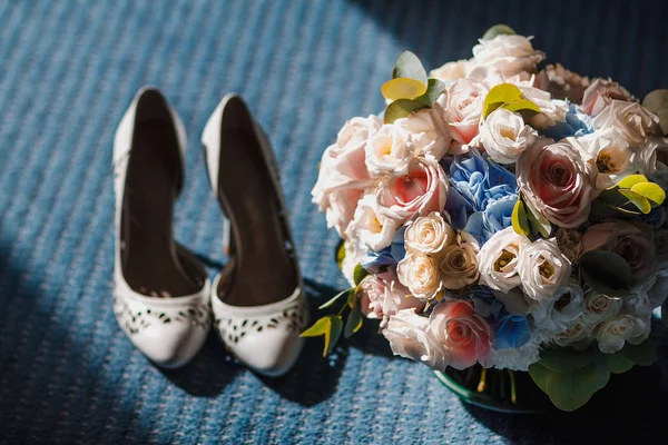 Trouwschoenen accessoires en bruid-bouquet verlicht door dramatische licht — Stockfoto