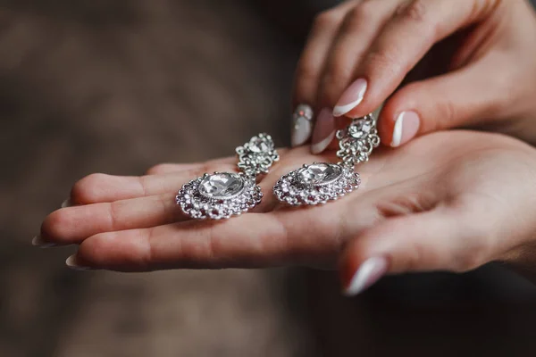 婚礼耳环戴在新娘的手、新娘的早晨饰物和珠宝饰物上 — 图库照片