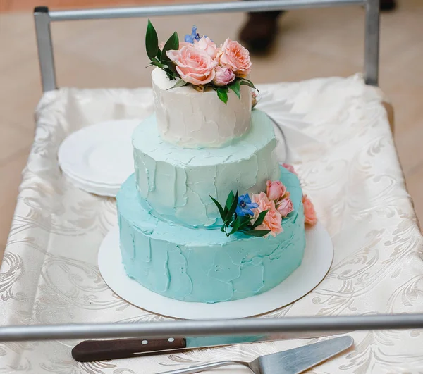 婚礼蛋糕在白色和蓝色的婚宴上, 装饰着鲜花 — 图库照片