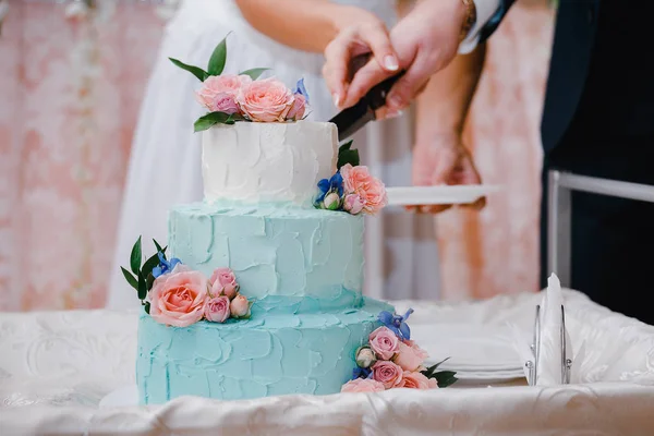 Belle coupe de gâteau festive turquoise par les jeunes mariés lors de la cérémonie de mariage — Photo
