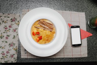 Meyve cheesecake çöl beyaz plaka ve Restoran masada akıllı telefon. Kopya alanı ile boş ekran ile akıllı telefon