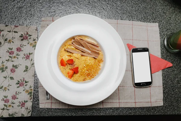 Meyve cheesecake çöl beyaz plaka ve Restoran masada akıllı telefon. Kopya alanı ile boş ekran ile akıllı telefon — Stok fotoğraf