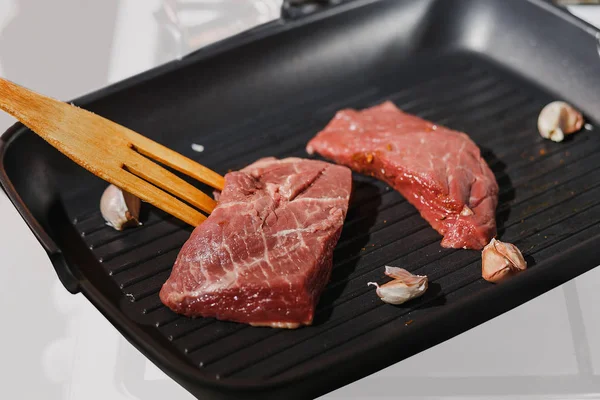 Kocken förbereder läckra nöt biff kött med vitlök på pan — Stockfoto