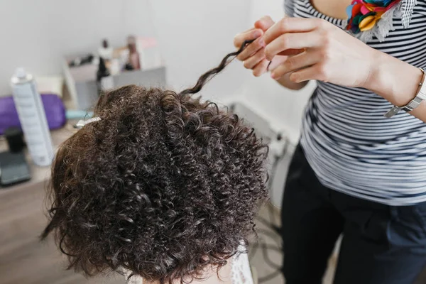 Gros plan d'un coiffeur bouclant cheveux noirs courts avec des fers à repasser . — Photo