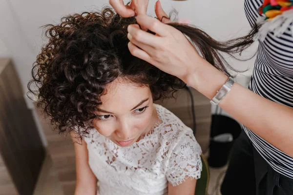 Καλλιτέχνης κομμωτής κάνοντας σγουρά hairstyle γοητευτική μελαχρινή γυναίκα νύφη με κοντά μαλλιά την ημέρα του γάμου. Εσωτερικό χώρο του Studio ομορφιάς — Φωτογραφία Αρχείου