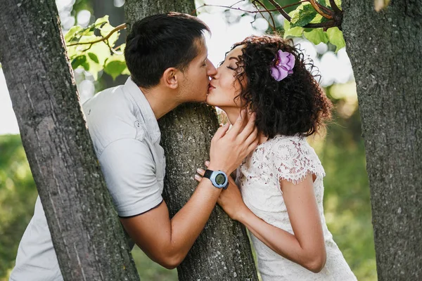 Portret van paar verliefd omarmen en kussen buiten in het park tussen de bomen — Stockfoto