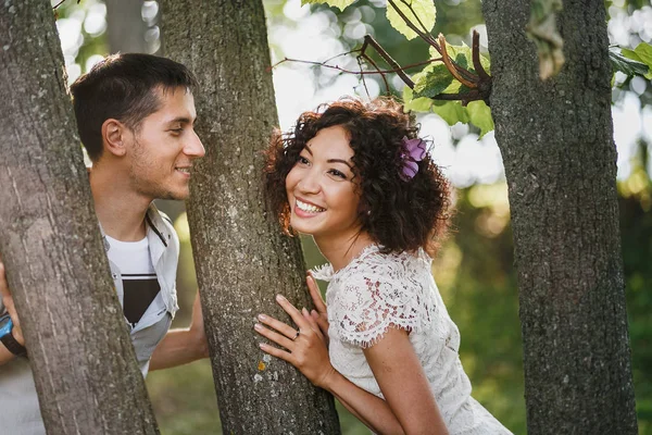 Влюбленные женщина и мужчина обнимаются и веселятся в летнем парке среди деревьев — стоковое фото