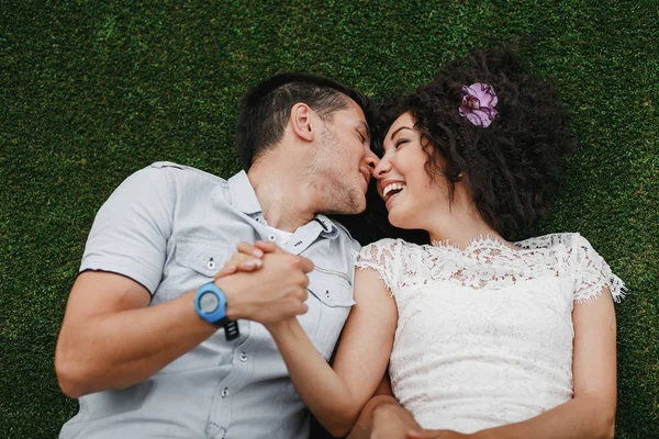 Junges niedliches Mischlingspaar auf Gras liegend. Verlobung Außenschuss — Stockfoto