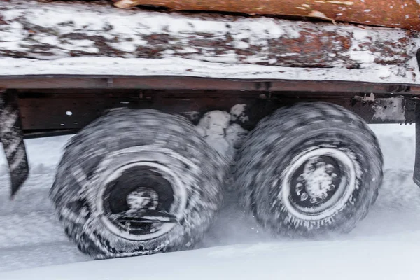 Θαμπός περιστρεφόμενοι τροχοί βαρέων φορτηγών ξυλείας το χειμώνα με αλυσίδες χιονιού — Φωτογραφία Αρχείου