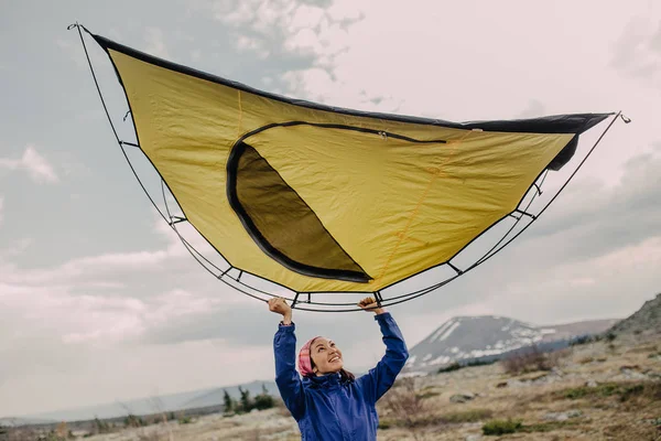 Mulher nas montanhas em um parque nacional monta uma tenda no acampamento — Fotografia de Stock