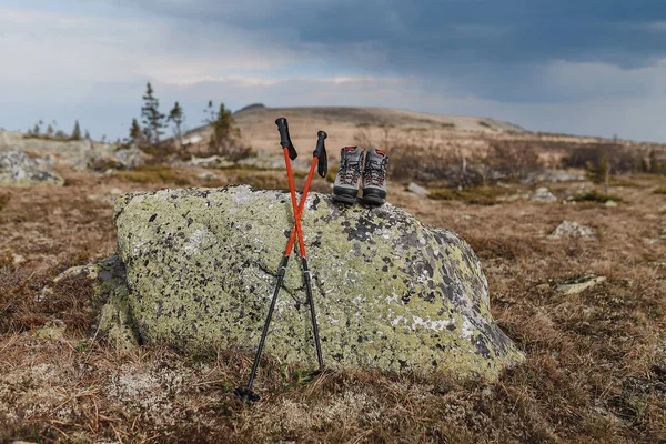 Kängor med vandringsstavar på gräset i våren Ural bergskedja bakgrunden — Stockfoto