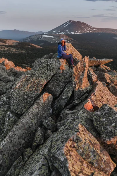 Mujer excursionista con teléfono inteligente en el acantilado pico de montaña al atardecer — Foto de Stock