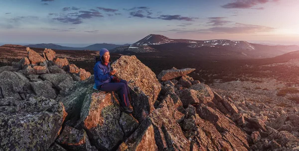 Žena tramp s chytrý telefon na horském vrcholu útesu na západ slunce — Stock fotografie