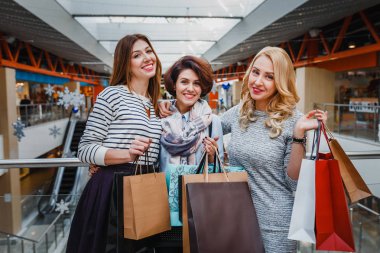 Genç kadın grup alışveriş merkezinde alışveriş torbaları ile süslenmiş Noel için